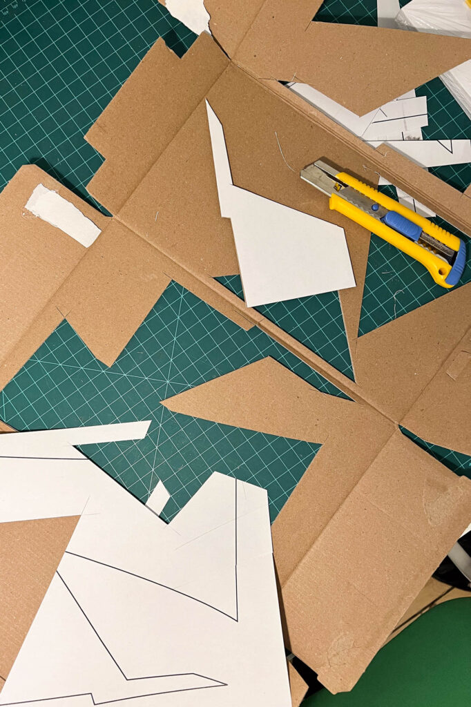 Overview of a cutting mat with pieces of cardboard and a box cutter.