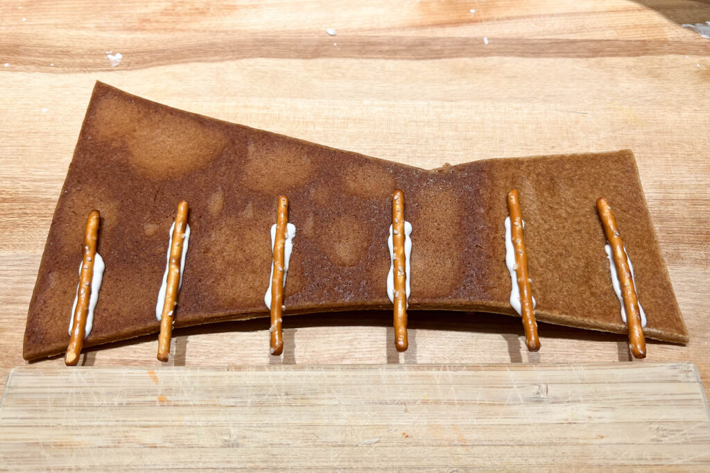 Pretzel sticks glued to a curved piece of gingerbread with royal icing.