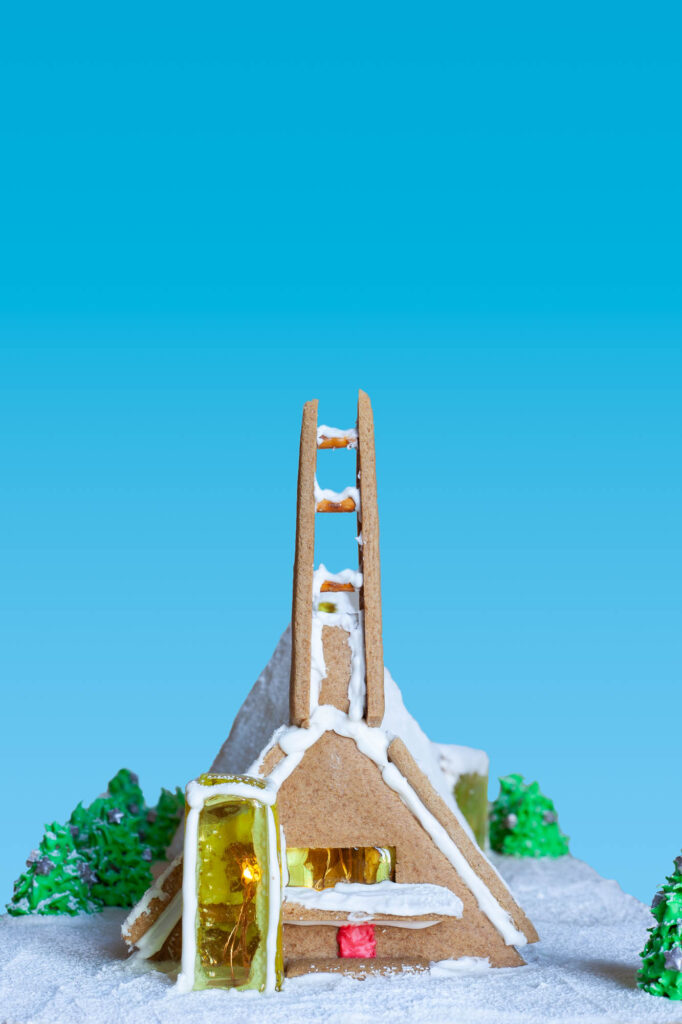 Gingerbread and candy glass architectural model of a modernist church. The model is lit from the inside.